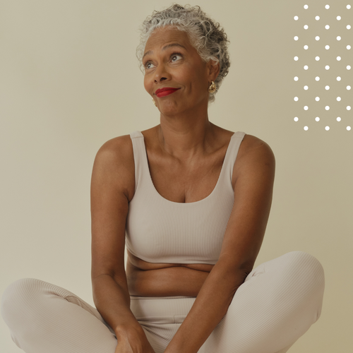 Woman in a beige tank top and pants sitting on a beige background