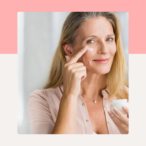 Woman applying cream to her face with a pink and white background