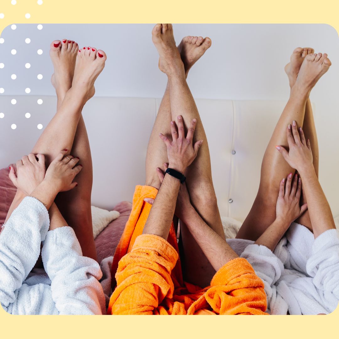 Three people in bathrobes with their legs and feet showing, sitting on a couch.
