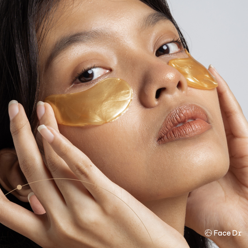 Woman with gold eye patches on a neutral background